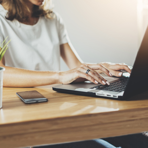 Woman typing on her laptop with no pain after her appointment with her orthopedic provider.